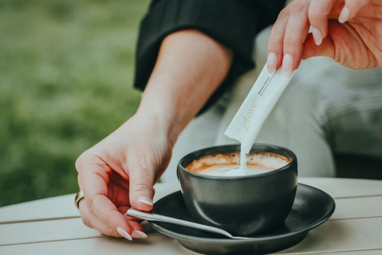 Hand pouring sweetener into an espresso cup on an outdoor table in Tuscany