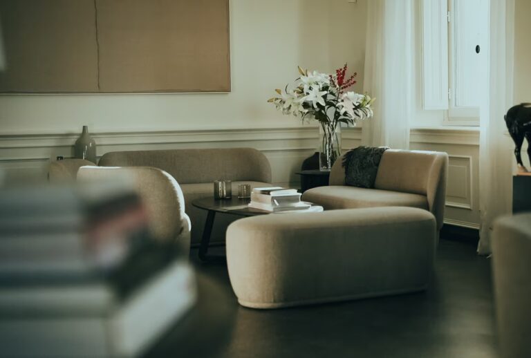 Elegant lounge area at One Belvedere Tuscany featuring books for slow living, fresh flowers, and soft natural light through large windows