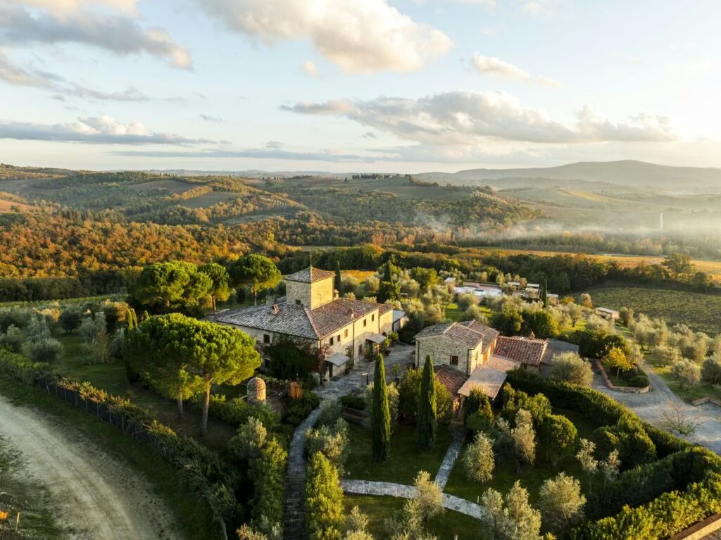 Aerial view of Locanda Le Piazze surrounded by rolling hills and vineyards in Chianti, Tuscany