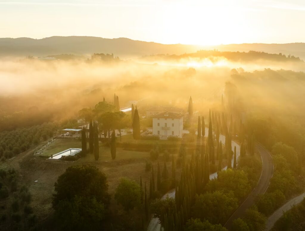 Photographing One Belvedere Tuscany from above, with the estate surrounded by cypress trees, olive groves and golden morning mist.